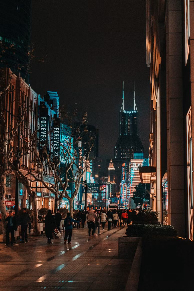 Die Nanjing Road bei Nacht mit Leuchtreklamen und Passanten